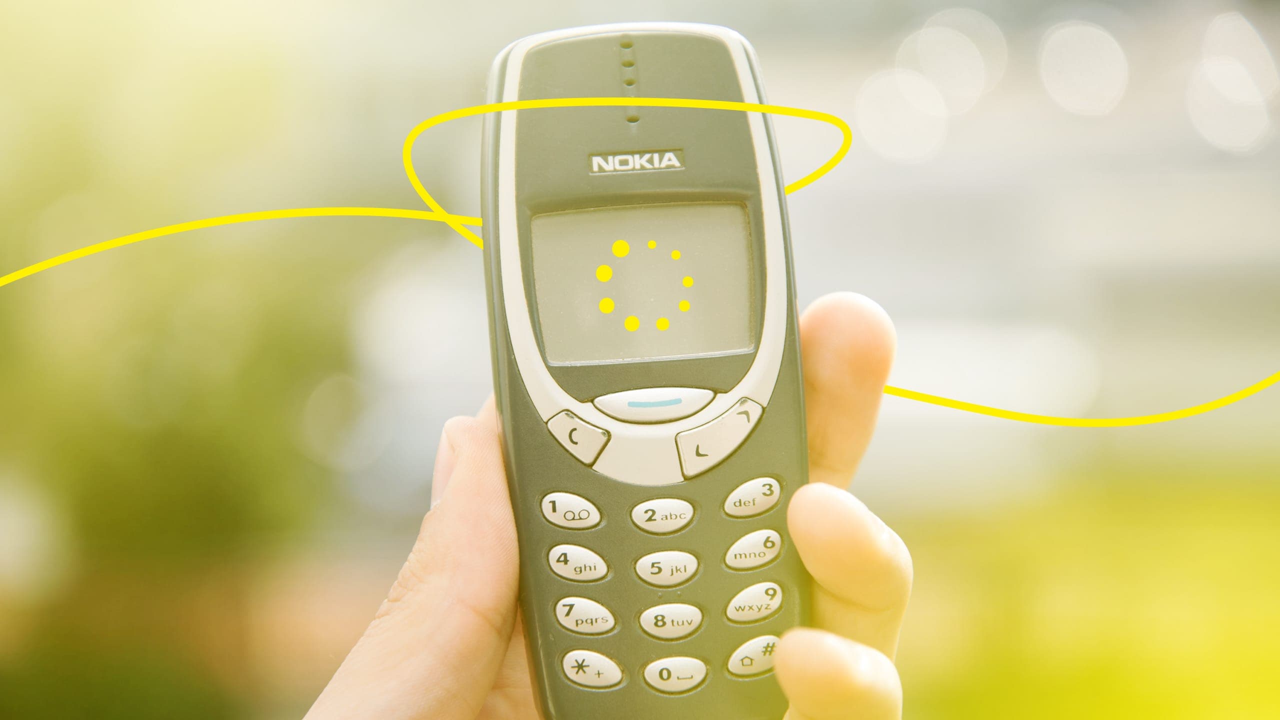 A hand holding up an old Nokia mobile phone, with an illustrated loading icon drawn on the screen